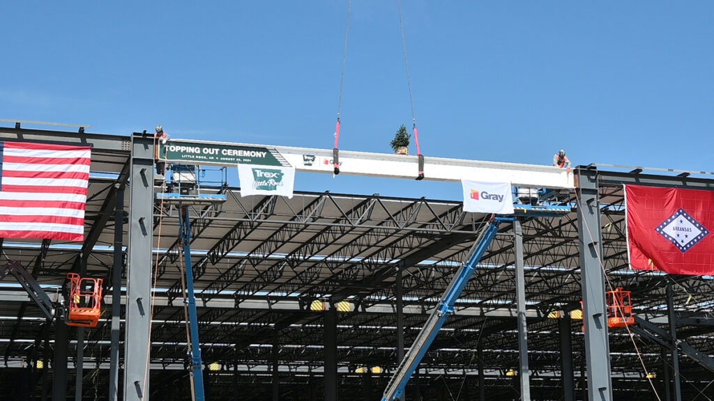 A construction worker assists with placing a beam during the Steel Topping Out Ceremony.